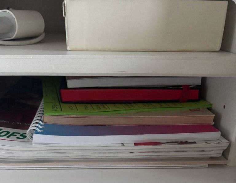 Ein Regal mit mehreren Stapeln von Schreibblöcken und Ordnern in verschiedenen Farben.