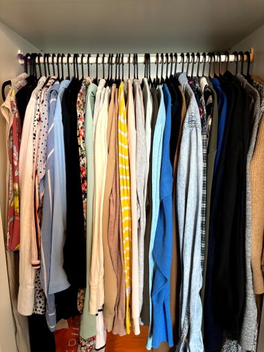 Kleiderschrank mit hängender Kleidung in unterschiedlichen Farben und Materialien - nach Saison sortiert